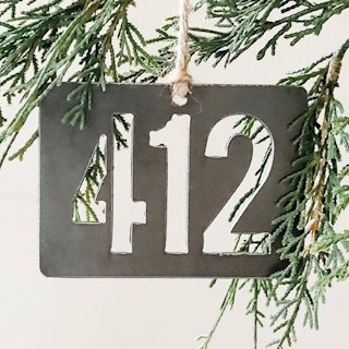 a metal "412" ornament hanging on a tree