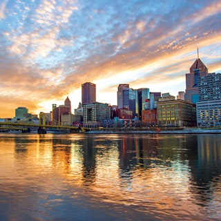 Pittsburgh city skyline reflects off the water during sunset